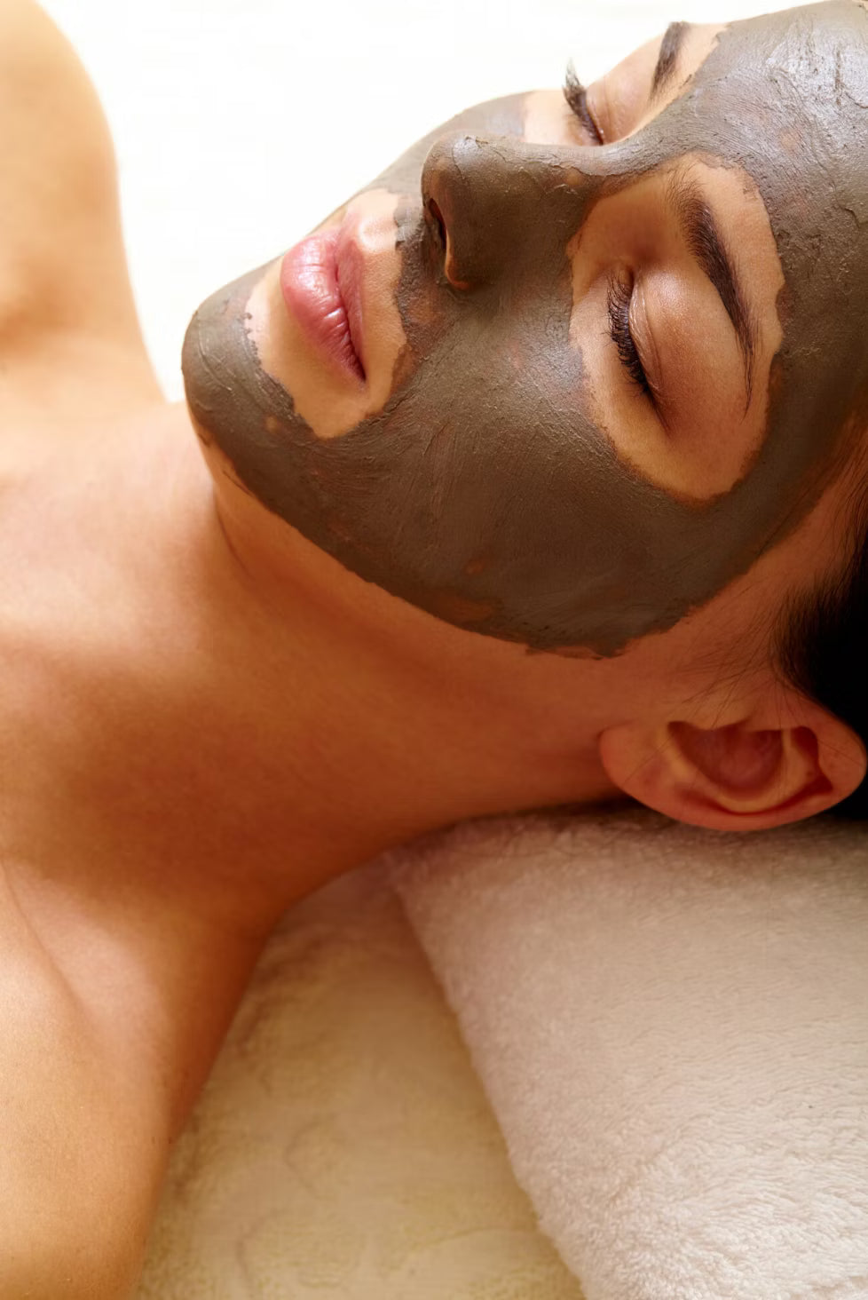 Woman with a clay facial mask relaxing during a facial